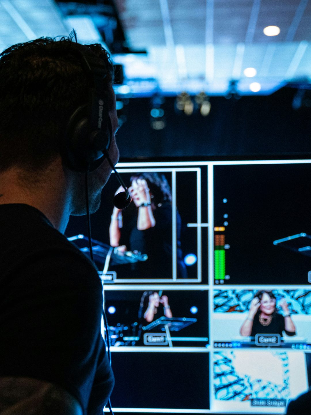 Production booth operator in a headset watching a multiviewer of live camera feeds